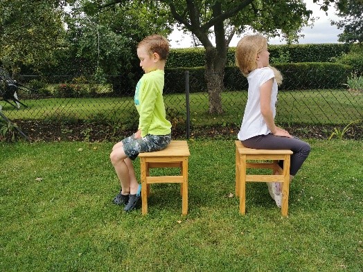 Two children sitting straight up, demonstrating a posture which is too straight