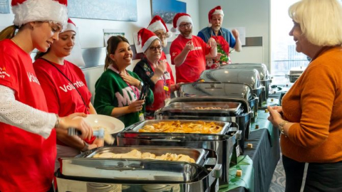 Volunteers serving Christmas meals to staff from metal chafing dishes.