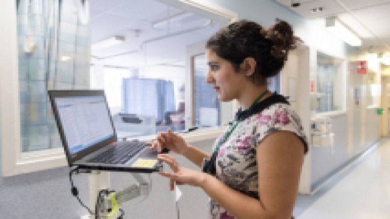 A member of staff standing at a computer on a hospital ward